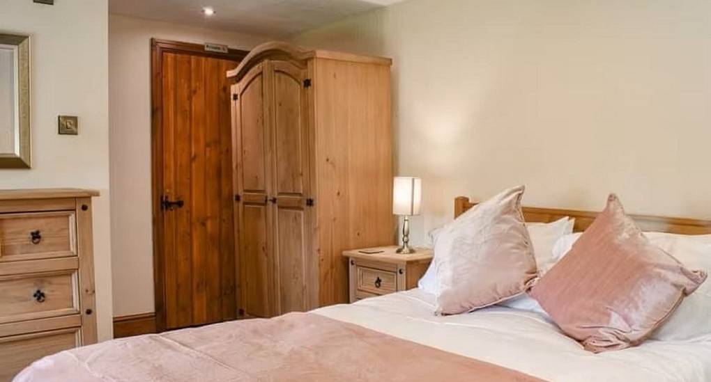 Large bedroom with double bed and pink covers